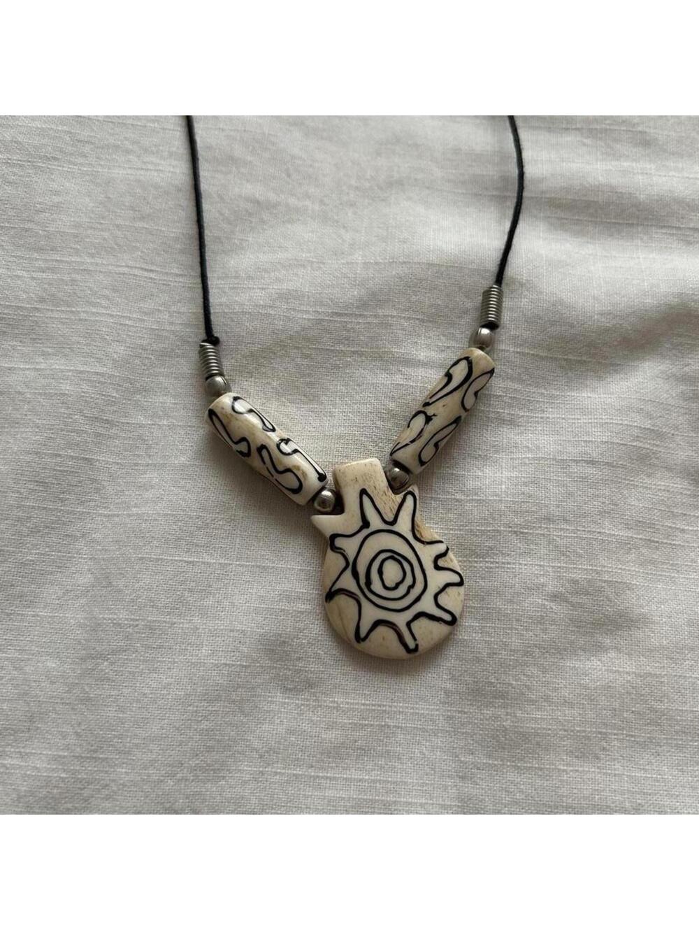 Carved bead cream sun motif necklace with cord